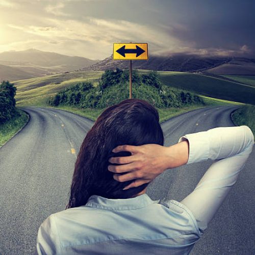 business woman in front of two roads thinking deciding hoping for best taking chance